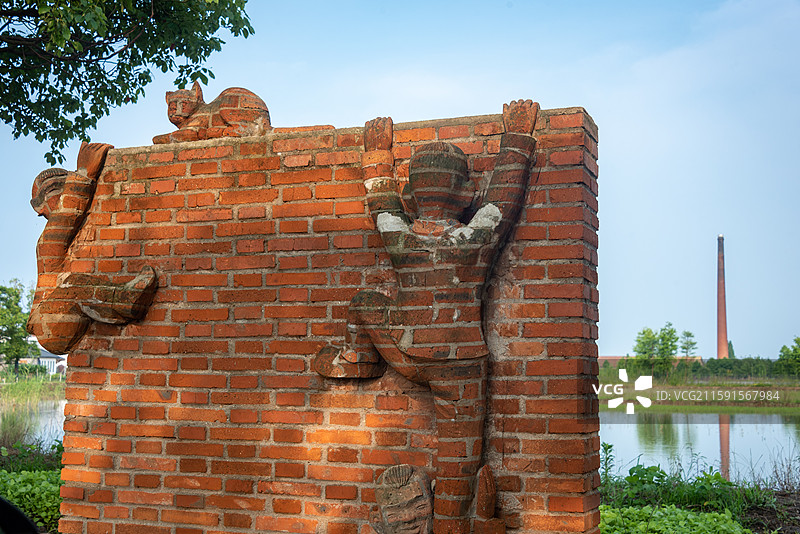 祝甸村内，砖制雕塑展现勇气与合作，背景自然环绕。图片素材