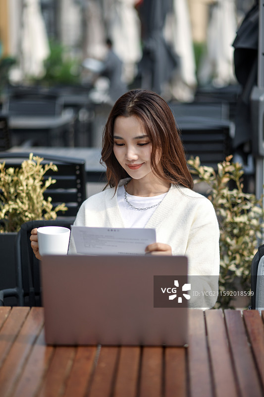 年轻女子在坐在咖啡厅户外用笔记本电脑图片素材