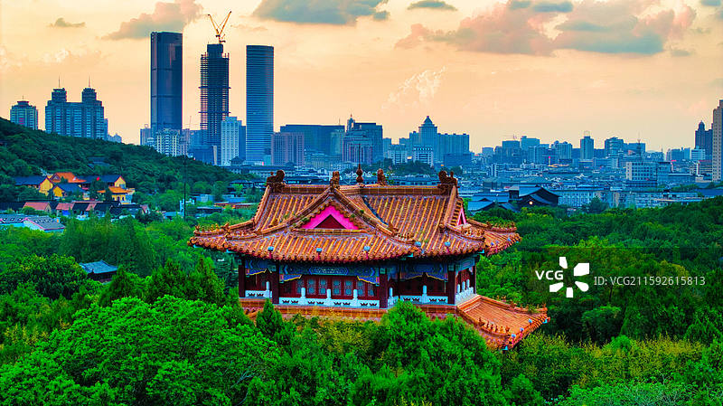 徐州彭祖园静立夕阳中，天空彩霞绚烂，远处闹市区轮廓清晰，自然静谧与城市烟火相融，勾勒出独特的暮色画卷图片素材