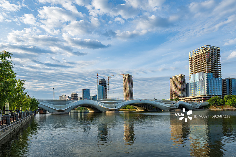 北京市通州区，京杭大运河上的“千荷泻露桥”，远景为建设中的运河商务区。图片素材