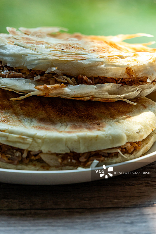 绿色虚化背景中的传统美食面食酥皮肉夹馍老面肉夹馍腊汁肉夹馍特写镜头图片素材