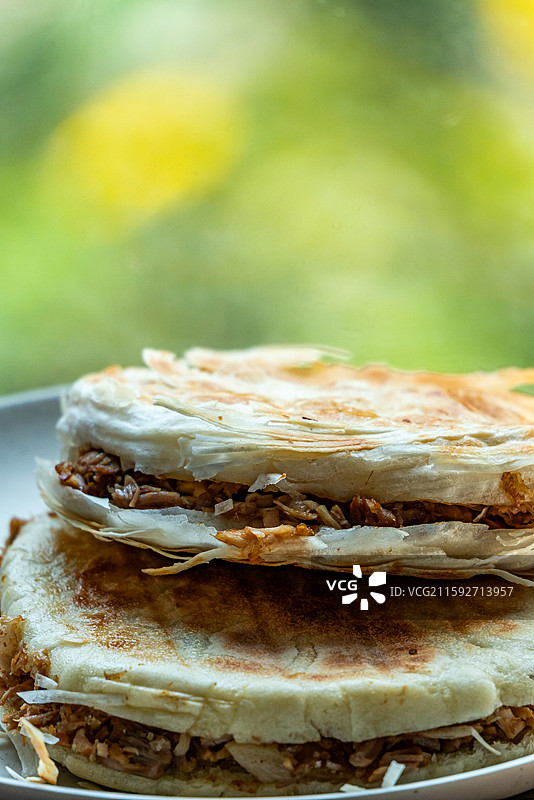 绿色虚化背景中的传统美食面食酥皮肉夹馍老面肉夹馍腊汁肉夹馍特写镜头图片素材