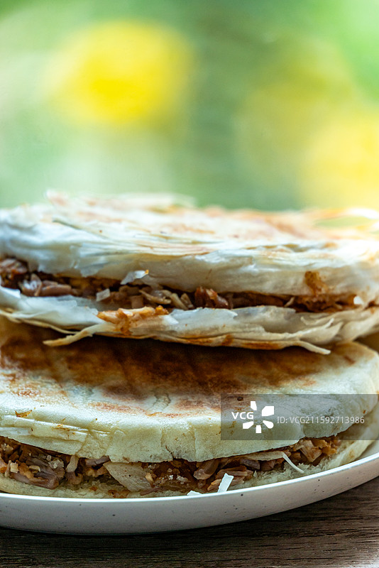 绿色虚化背景中的传统美食面食酥皮肉夹馍老面肉夹馍腊汁肉夹馍特写镜头图片素材