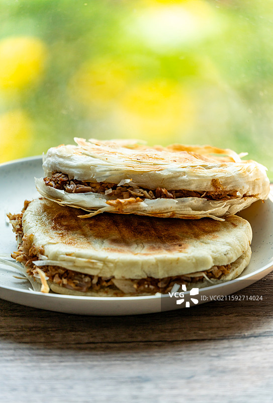 绿色虚化背景中的传统美食面食酥皮肉夹馍老面肉夹馍腊汁肉夹馍特写镜头图片素材