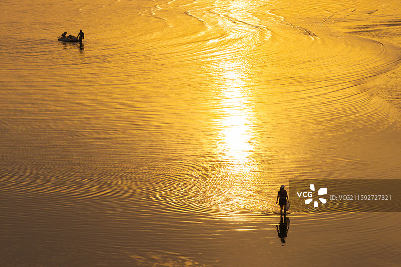 日出时分的烟台金沙滩景区海滩的讨海人图片素材