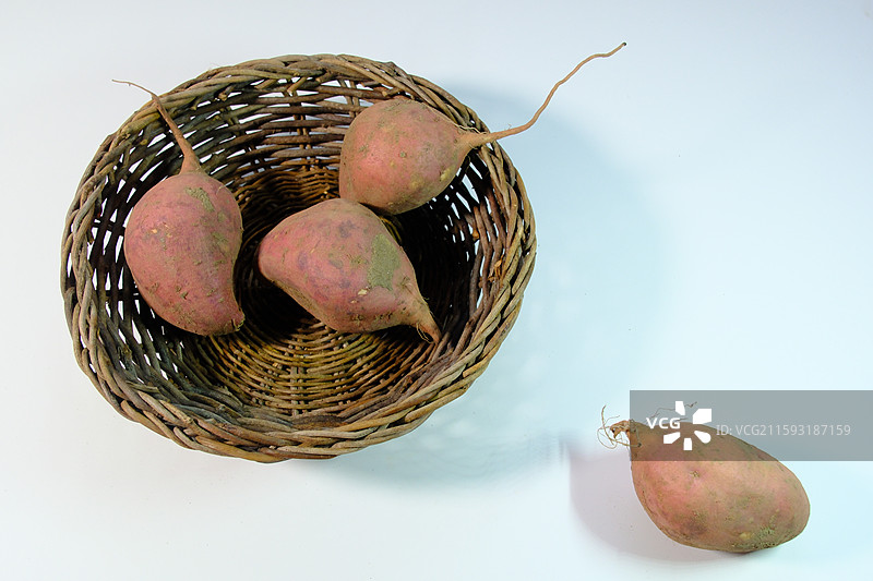 白色背景下。柳编篮子筐里的新鲜红薯图片素材