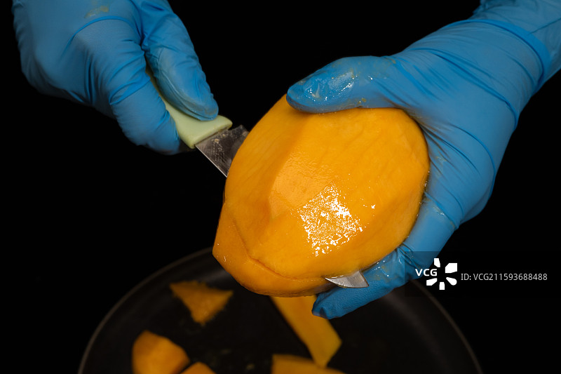 戴蓝色手套的人正在切芒果图片素材