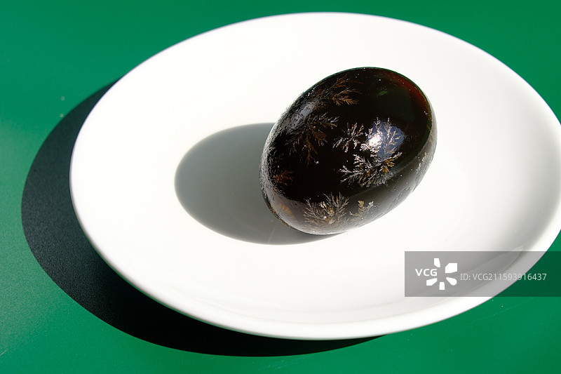 阳光下。绿色白色背景下盘子里的松花蛋。皮蛋。特写。设计素材图片素材