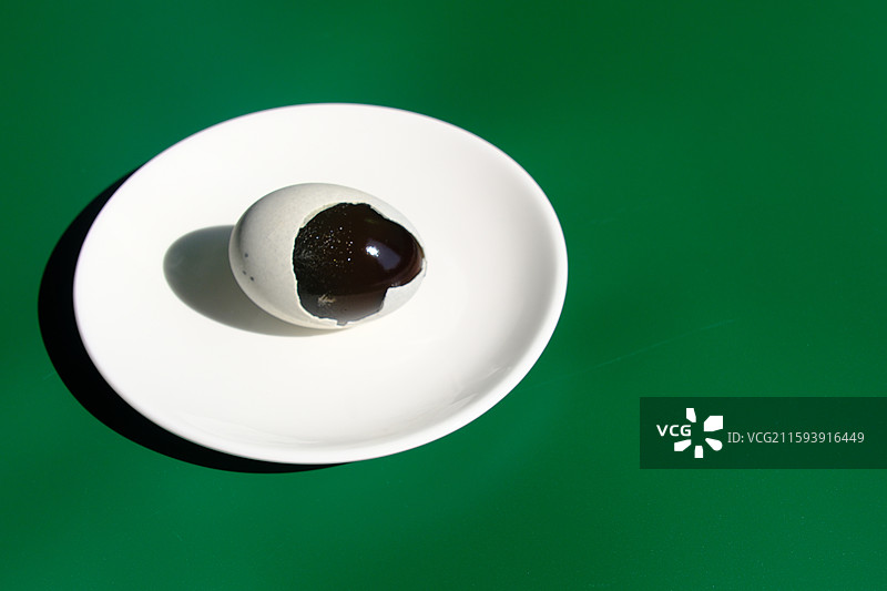 阳光下。绿色白色背景下盘子里的松花蛋。皮蛋。特写。设计素材图片素材