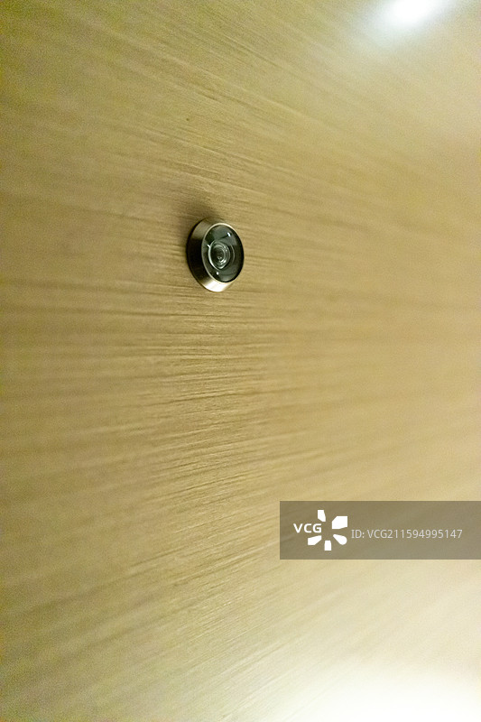 中国酒店宾馆民宿招待所住宿拍摄主题，黄色木门上查看访客的猫眼设备，室内人的手图像摄影图片素材