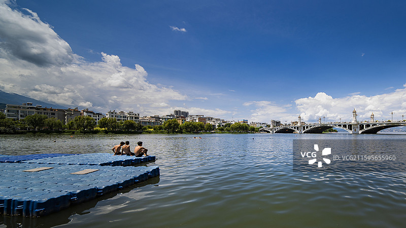在西洱河里游泳的少年和兴盛大桥图片素材