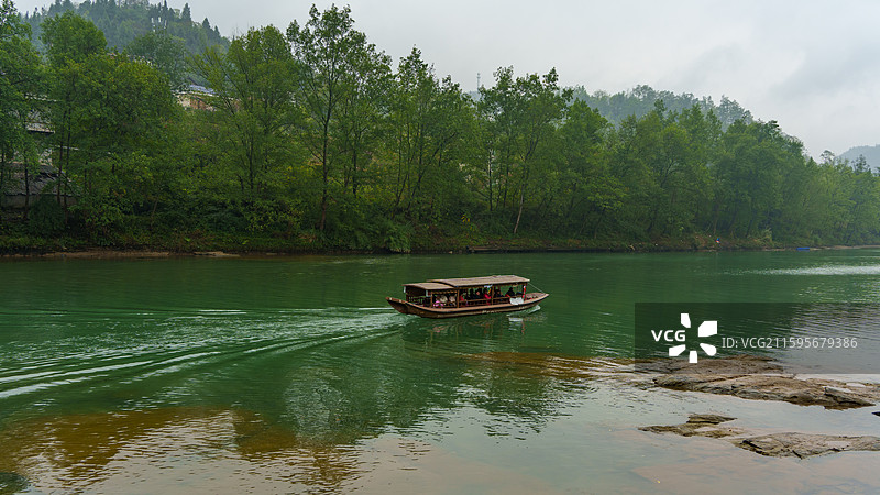 行驶在边城茶峒洪安古镇附近黔湘渝边界碧绿河流上的游船图片素材