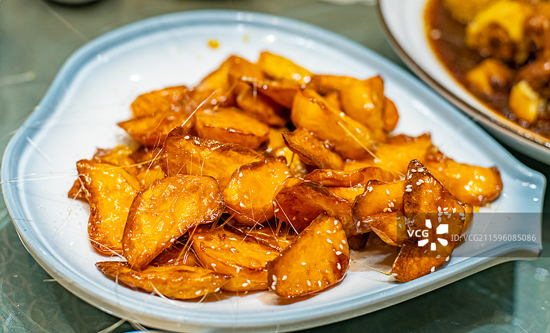 中国餐饮行业饮食产业，传统经典中国食品，一盘子正在拉丝的拔丝地瓜拔丝山药，室内无人图像图片素材