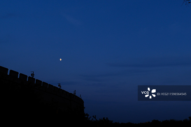 傍晚黄昏夜晚蓝色天空月牙月亮月色月夜。正定古城墙城门楼。树梢。自然风光背景图图片素材