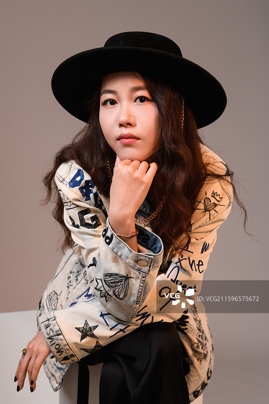 在灰色背景下的戴帽子的年轻女子肖像图片素材