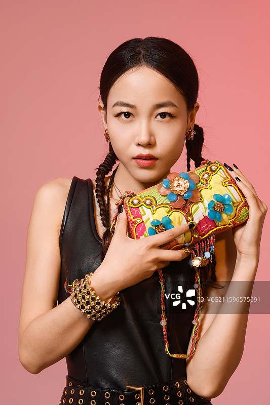 粉红色背景下拿着珠宝包包的女人图片素材