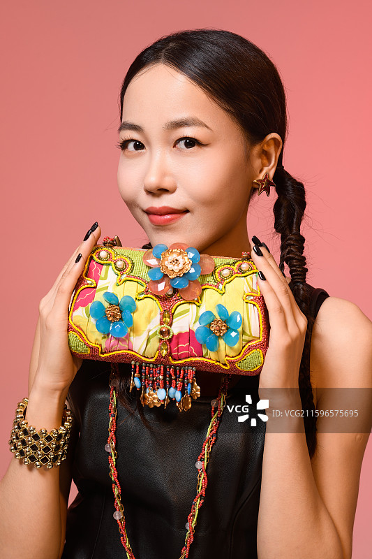 粉红色背景下拿着珠宝包包的女人图片素材