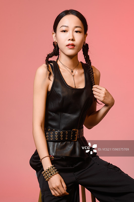 粉红色背景下梳着辫子的时尚美女肖像图片素材