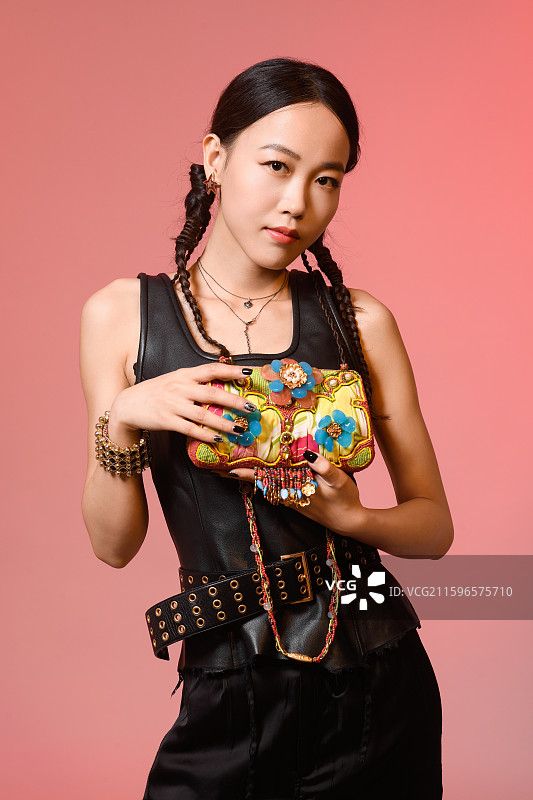 粉红色背景下拿着珠宝包包的女人图片素材
