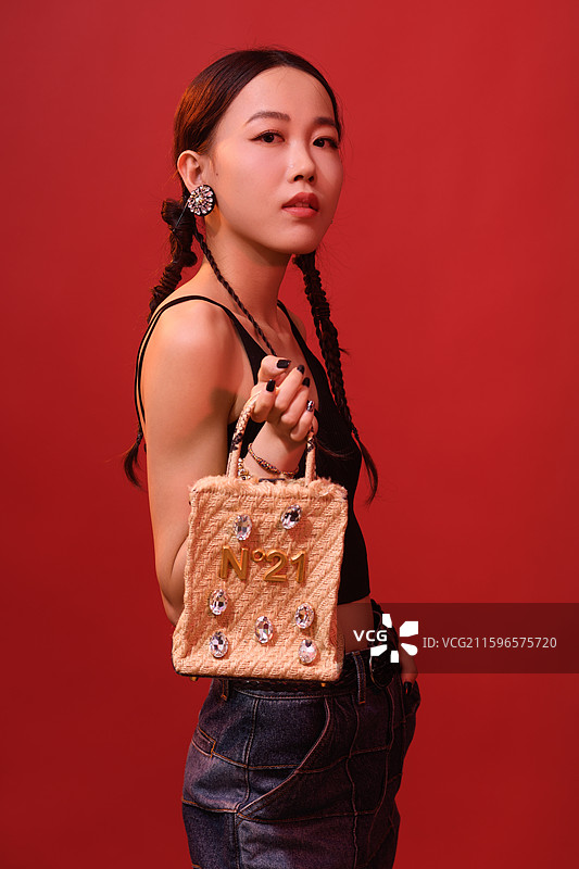 在红色背景下拿着包的年轻女子时尚肖像图片素材