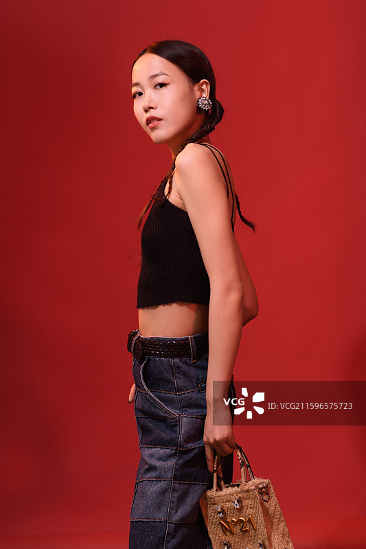 在红色背景下拿着包的年轻女子时尚肖像图片素材