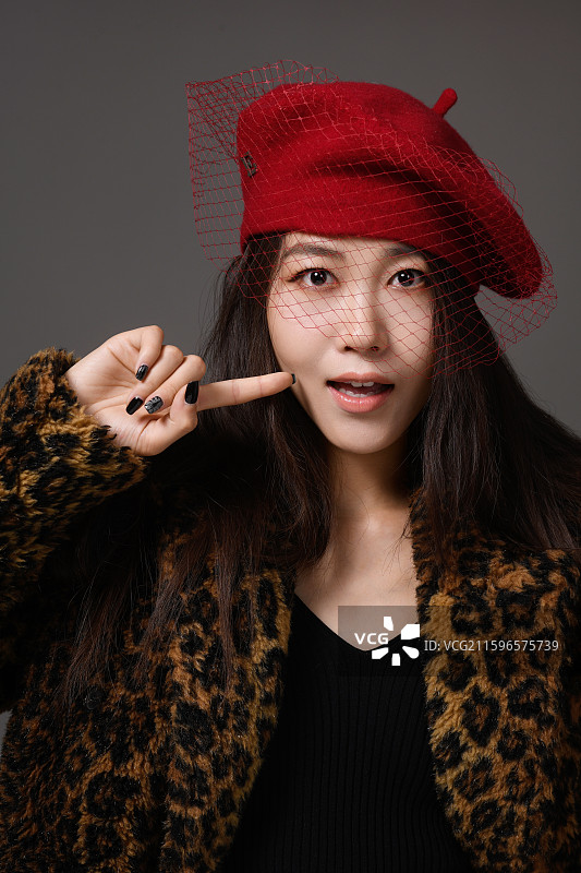 灰色背景下戴帽子的年轻女子的特写肖像图片素材