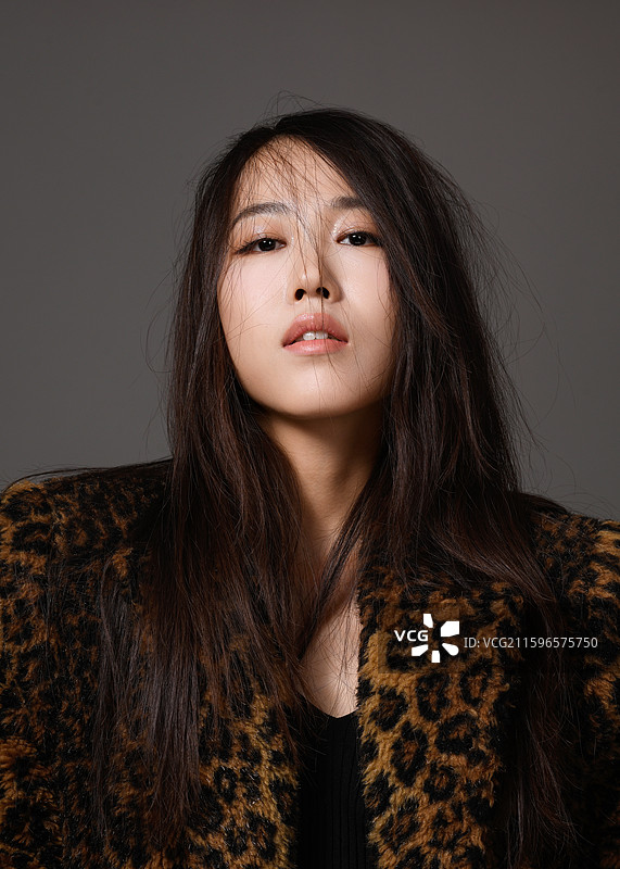 灰色背景下身穿豹纹大衣的年轻女子肖像图片素材