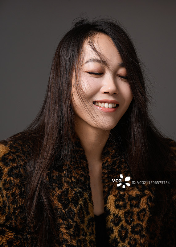 灰色背景下身穿豹纹大衣的年轻女子肖像图片素材