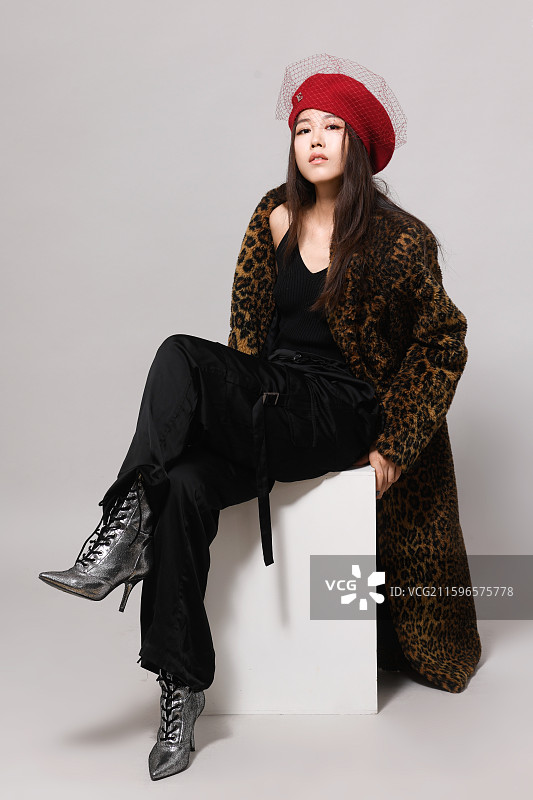戴帽子坐在立方体上的年轻女子影棚全身像图片素材