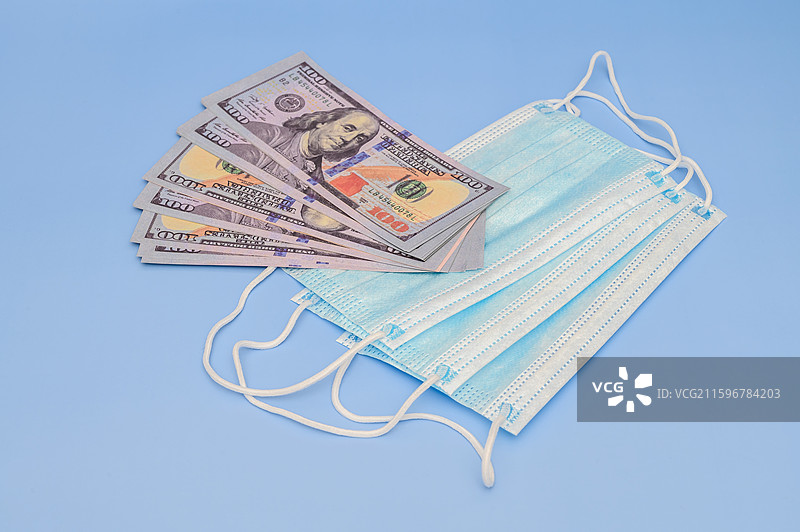 蓝色背景上的口罩和美元疫情概念图片素材