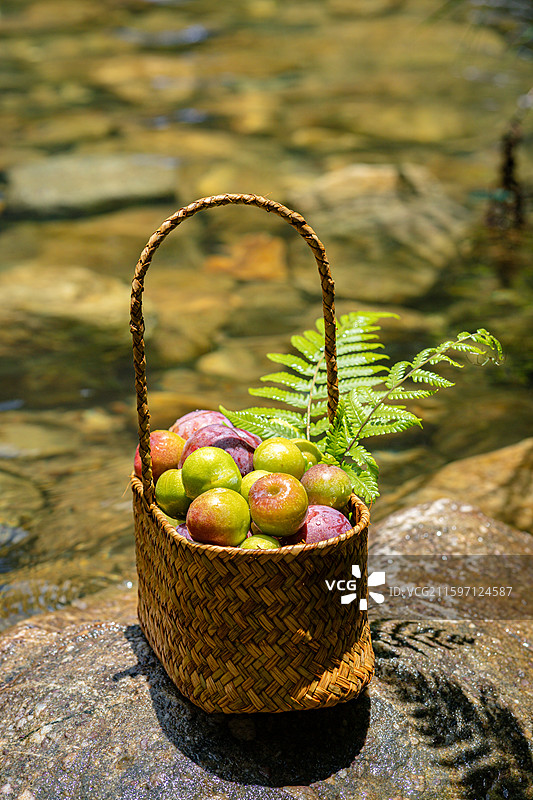 溪流中石头上摆放的新鲜水果果篮图片素材