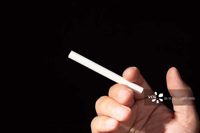 黑色背景下，手里拿着香烟，吸烟与健康问题图片素材
