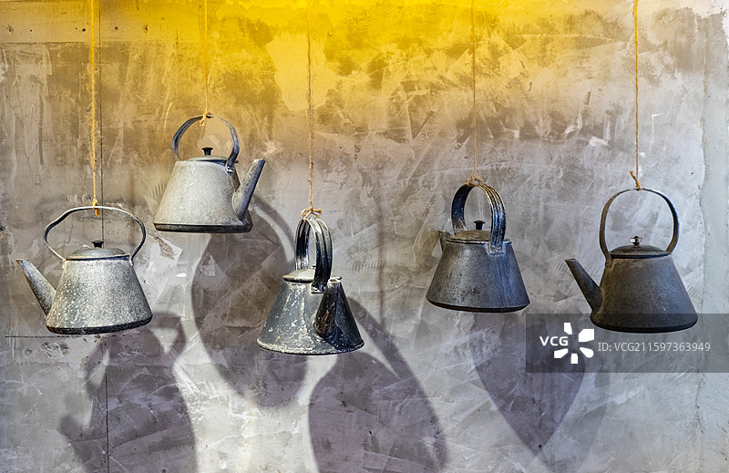 中国传统家用用品拍摄主题，传统家用设备用品，墙壁上悬挂的传统的铁艺铁质烧水壶，室内无人图像摄影图片素材