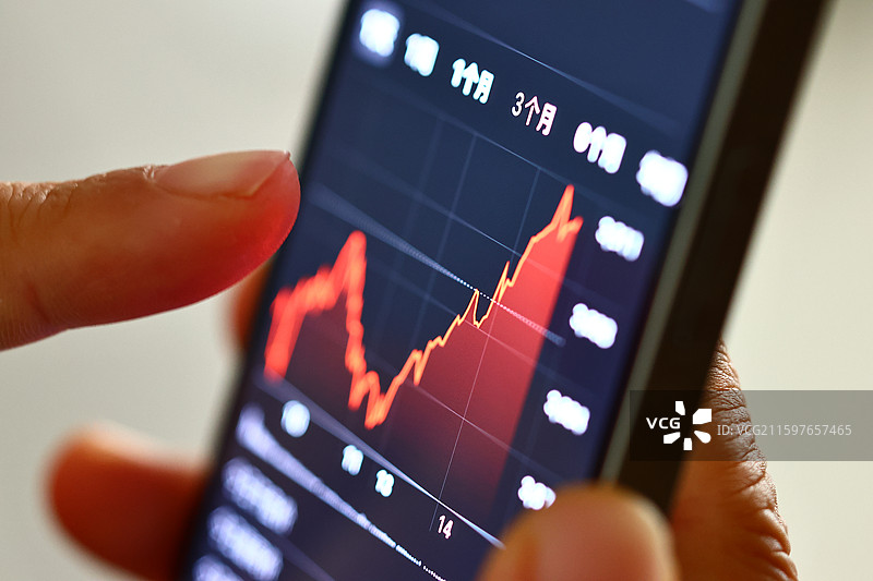 手持智能手机的人手分析股市K线动态财务图表图片素材