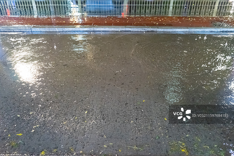 中国自然天气气候拍摄主题，下雨天马路公路街道雨水落在水泥地地面上溅起大量的水花，户外夜晚无人图像摄影图片素材