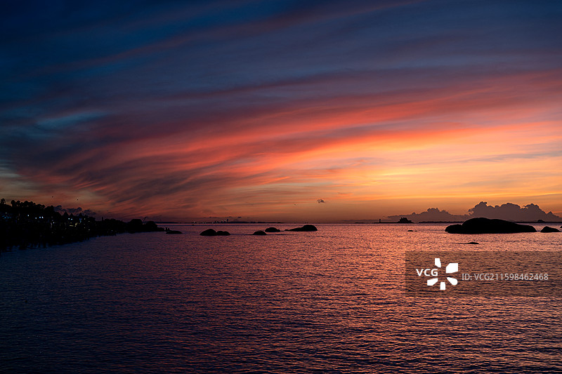 厦门黄厝海滩日出朝霞火烧云海景日落天空渐变云霞水面反射岩石剪影全景构图图片素材