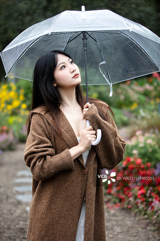 持透明雨伞的棕色开衫女子于繁花旁——浪漫唯美风格图图片素材