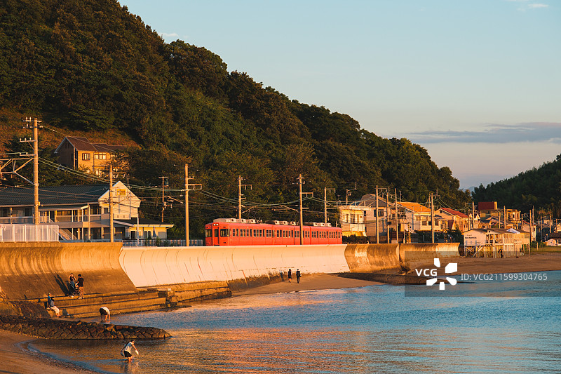 日本爱媛县松山市梅津寺车站，日落时分列车驶过海滩图片素材