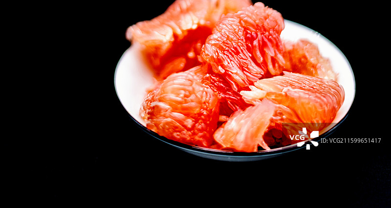 黑色背景下盘子中红柚柚子水果果肉的高角度视图图片素材