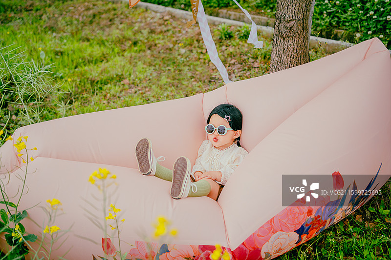 春天的油菜花田野里，女孩子和懒人沙发风筝的 快乐的时光图片素材