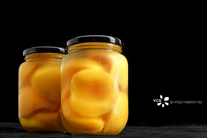 黑色背景上的一玻璃瓶童年美食零食黄桃罐头特写图片素材