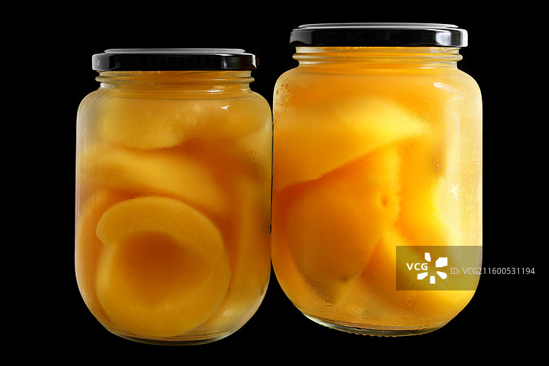 黑色背景上的一玻璃瓶童年美食零食黄桃罐头特写图片素材