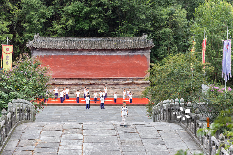 武当山龙泉观景区 小男孩观看在明代天津桥与照壁前习武的学生图片素材