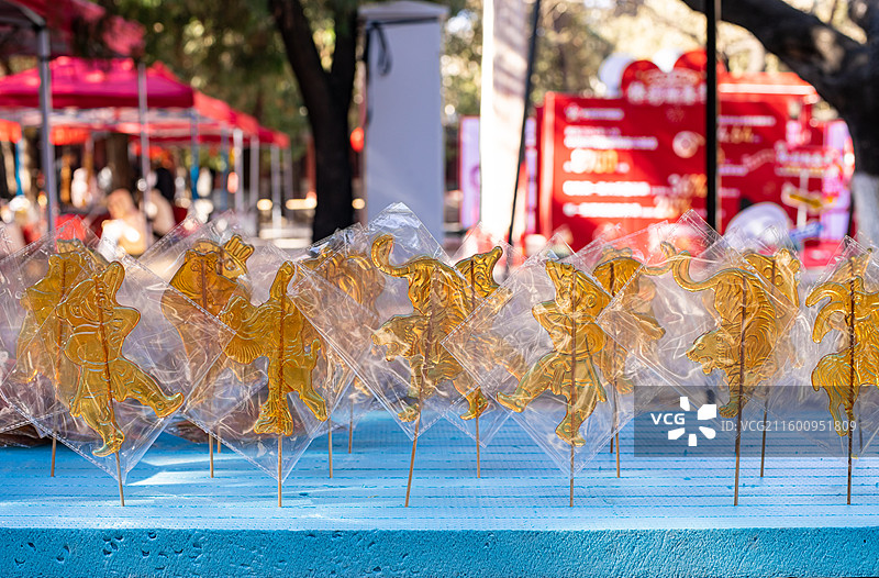 中国传统文化手艺拍摄主题，一排包装好的老虎山羊奥特曼熊二小猪佩奇孙悟空糖画，户外无人白昼图像摄影图片素材