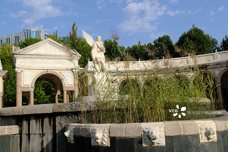 石家庄水上公园蓝天白云下一对拥抱的欧洲男女爱人情侣雕像雕塑。欧式建筑倒影图片素材