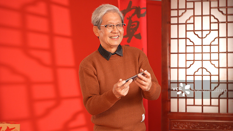 手拿手机玩网游的老年人图片素材
