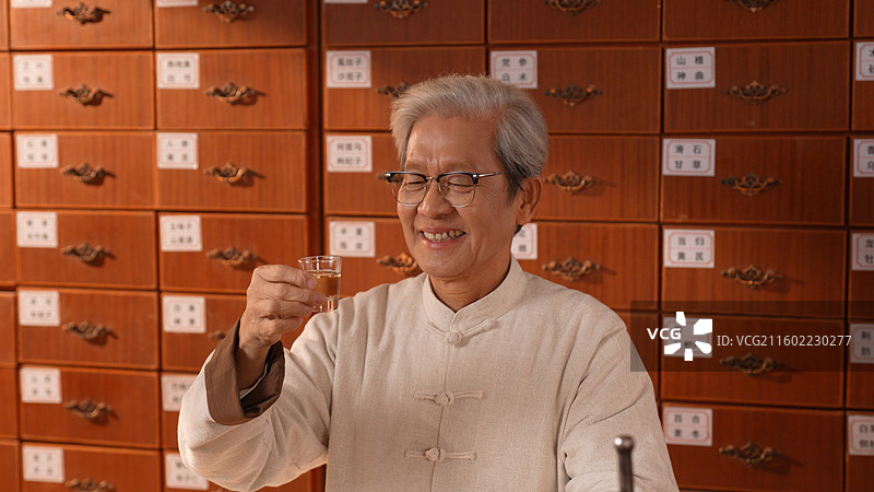 手拿酒杯喝酒的老年医生图片素材