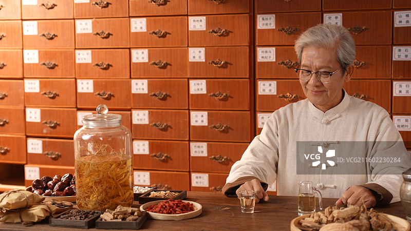 手拿酒杯喝酒的老年医生图片素材