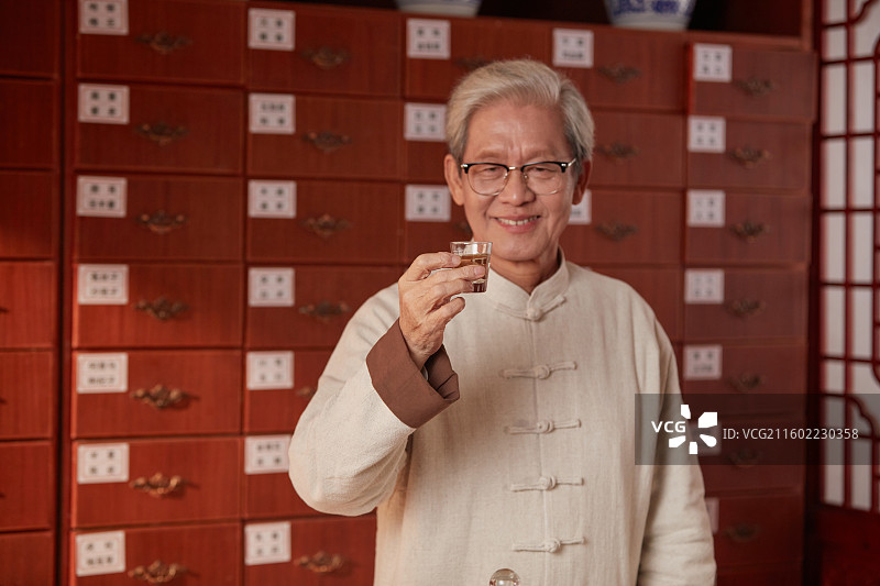 手拿酒杯喝酒的老年医生图片素材