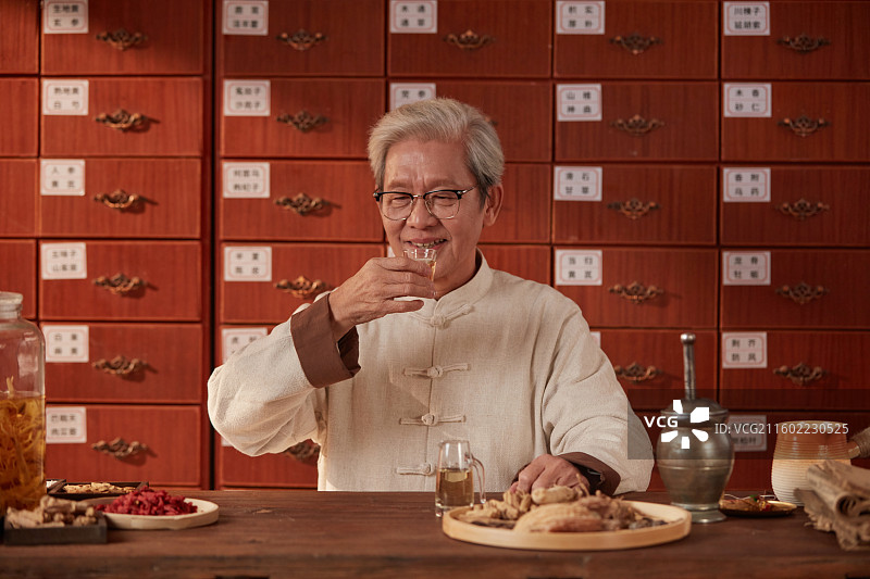 手拿酒杯喝酒的老年医生图片素材